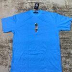 Sky blue streetwear t-shirt with a small central graphic illustration of a cartoon astronaut wearing a spacesuit, custom DTF printed by Whavieprints.