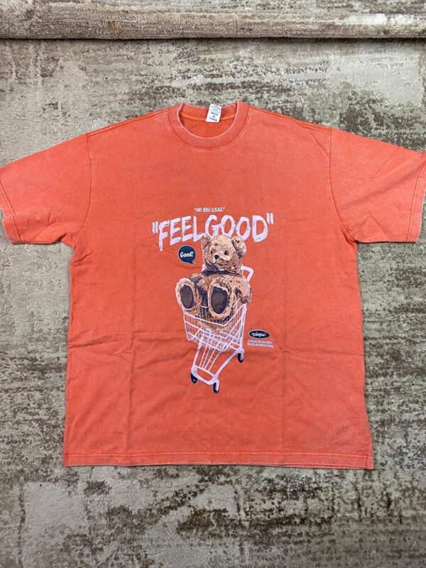 Vintage-wash orange streetwear t-shirt featuring a graphic of a brown teddy bear in a shopping cart under 'Feel Good' text, custom DTF printed by Whavieprints.